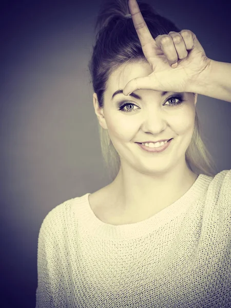 Frau zeigt Verlierer-Geste mit l auf der Stirn — Stockfoto