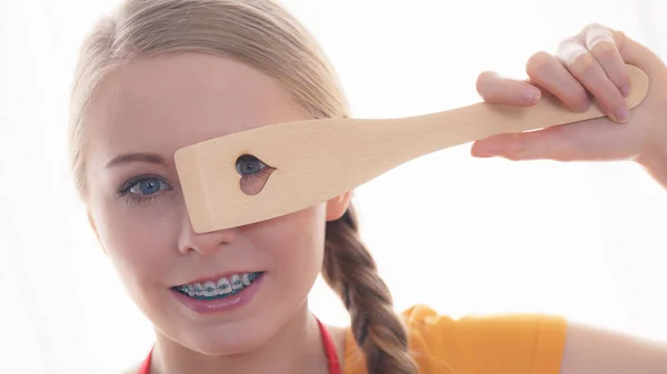 Woman holding wooden spatula with heart — Stock Photo, Image