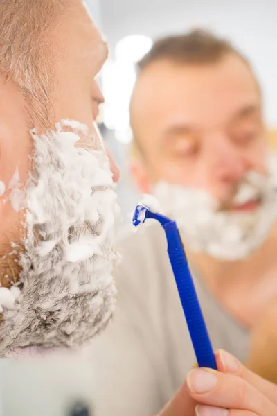 Guy shaving his beard in bathroom — Stock Photo, Image