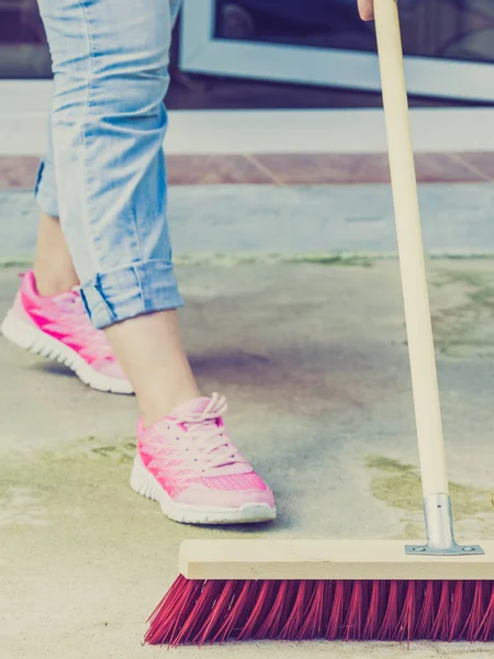 Mujer usando escoba para limpiar patio trasero — Foto de Stock