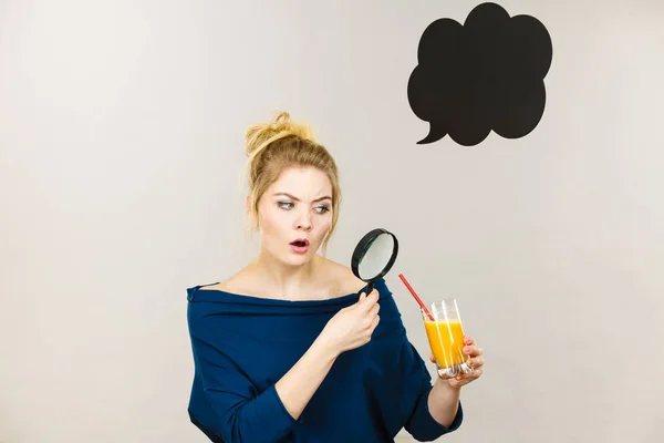 Kvinna med förstoringsglas undersöker juice — Stockfoto