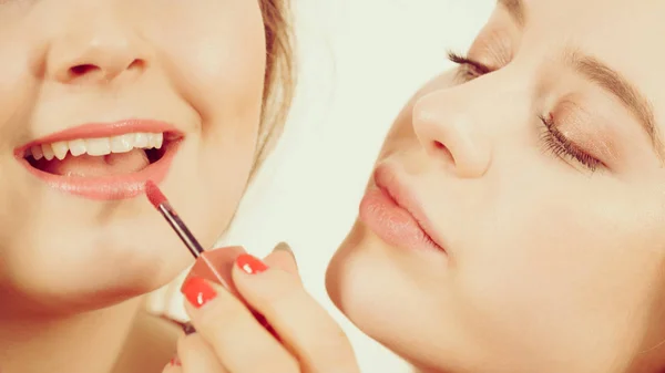 Woman applying her friend lipstick on lips — Stock Photo, Image