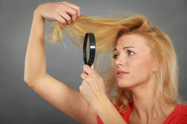 Woman looking at hair through magnifying glass — Stock Photo, Image