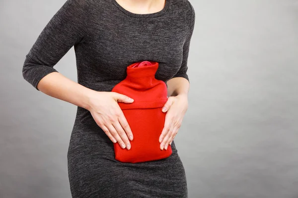 Mujer sintiendo calambres estomacales sosteniendo botella de agua caliente —  Fotos de Stock