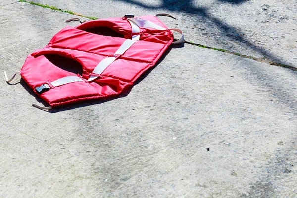 Life jacket lying on gray concrete floor ground — Stock Photo, Image