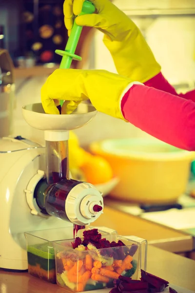 Kadın meyve sıkacağı makinesinde sebze suyu yapıyor. — Stok fotoğraf