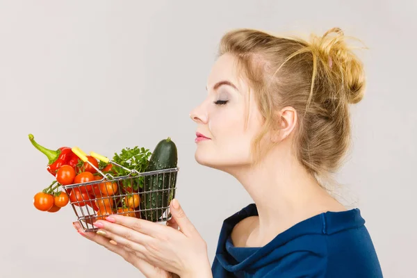 Mulher segura cesta de compras com legumes, cheirando — Fotografia de Stock