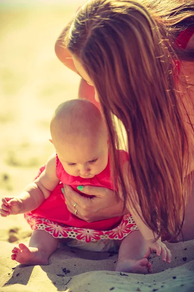 Donna che abbraccia bambino sulla spiaggia vicino all'acqua — Foto Stock