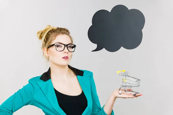 Thinking business woman holding small tiny shopping cart — Stock Photo, Image