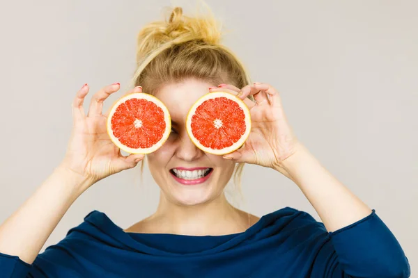 Vrouw met vruchten grapefruit helft op ogen — Stockfoto