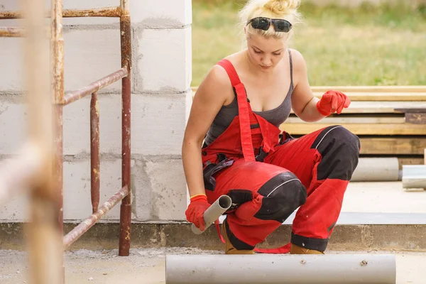 Femme installant des tuyaux sur le chantier de construction — Photo