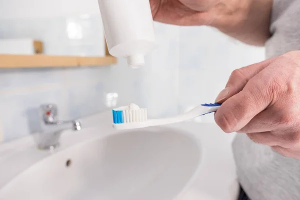 Pessoa que põe pasta de dentes na escova de dentes — Fotografia de Stock