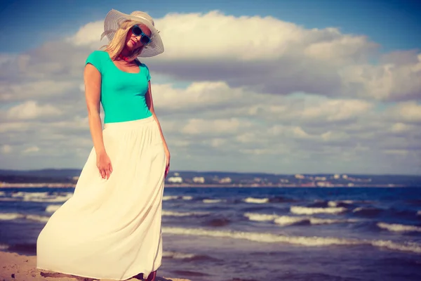 Blonde vrouw dragen jurk wandelen op strand — Stockfoto