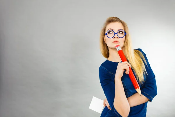 Mujer confusa sostiene papel de lápiz grande en la mano — Foto de Stock