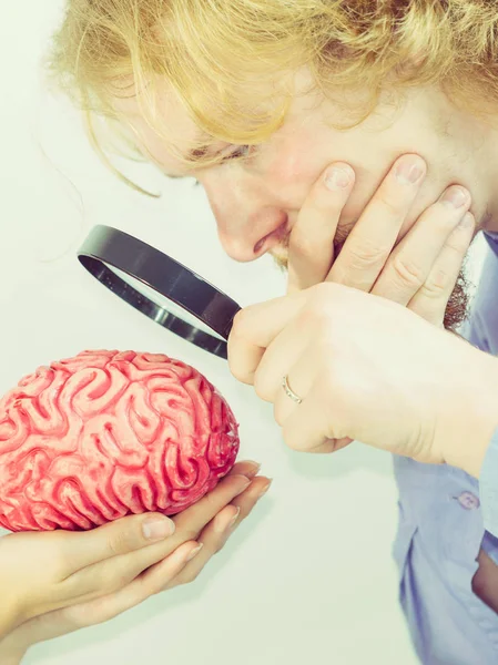 Hombre investigando cerebro humano usando lupa —  Fotos de Stock