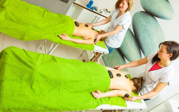 Massage mit heißen Steinen in Kosmetikerin — Stockfoto