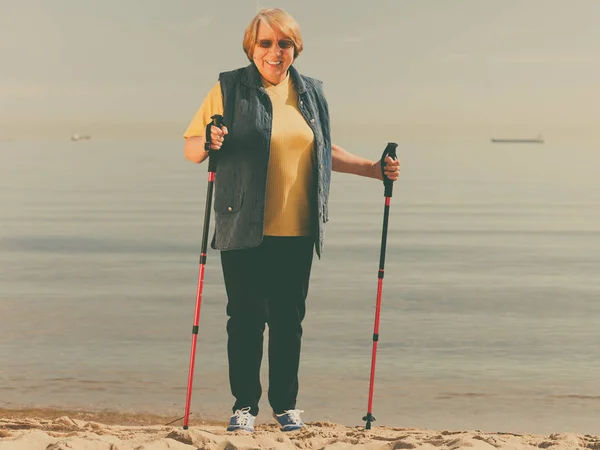 Seniorin übt Nordic Walking am Strand — Stockfoto