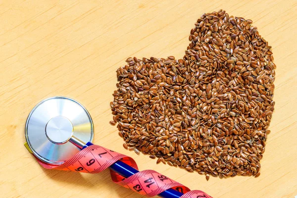 Raw flax seeds heart shaped and stethoscope — Stock Photo, Image