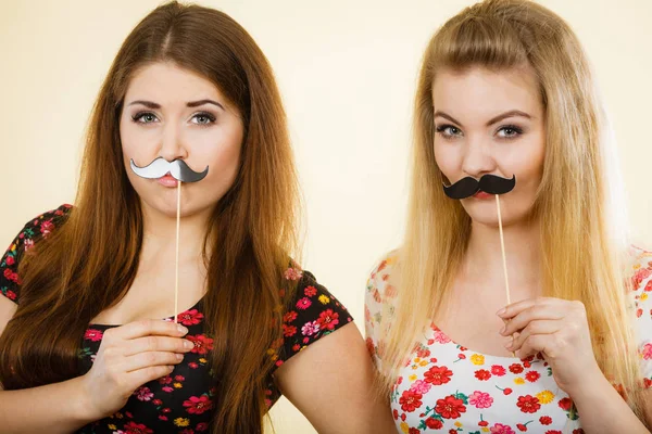 Dos mujeres felices sosteniendo bigote falso en palo —  Fotos de Stock