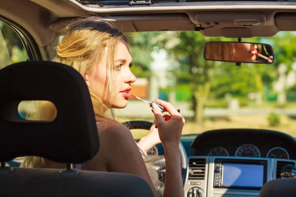 女の子は車を運転しながらメイクアップを適用します. — ストック写真