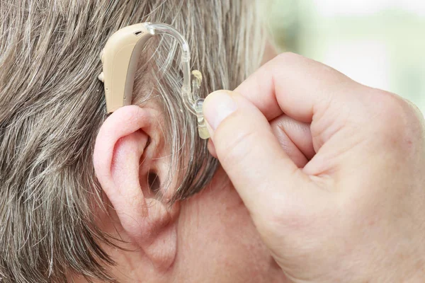 Fechar a mulher idosa usando aparelho auditivo — Fotografia de Stock