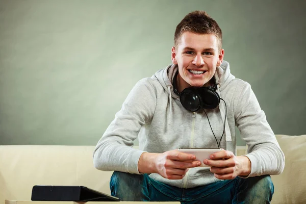 Homme sur canapé avec casque smartphone et tablette — Photo