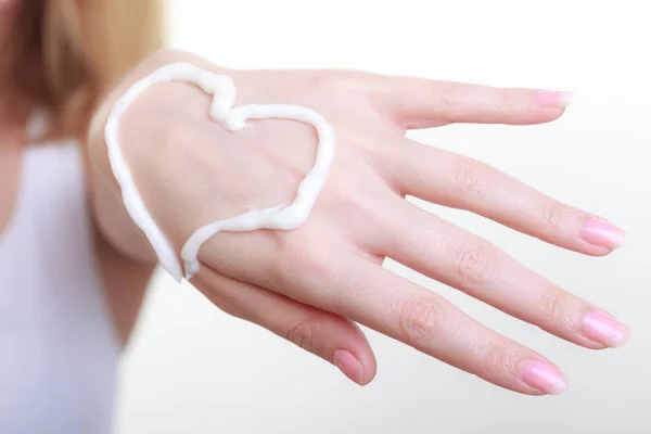 Crema sulla mano della donna, forma di cuore — Foto Stock