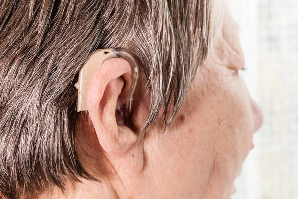 Gros plan femme âgée en utilisant une aide auditive — Photo