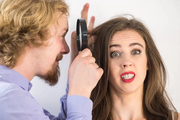 Homem olhando para o cabelo da mulher através de magnífica — Fotografia de Stock