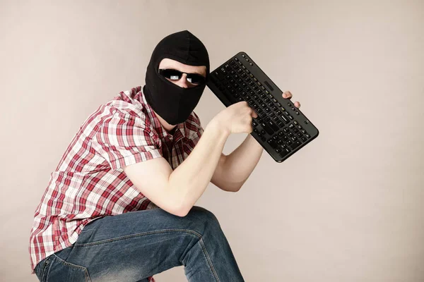 Uomo che indossa passamontagna tenendo la tastiera — Foto Stock