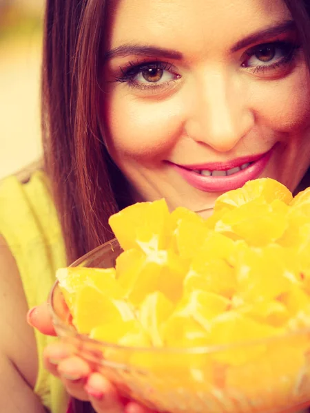 Mujer sostiene cuenco lleno de frutas de naranja en rodajas — Foto de Stock