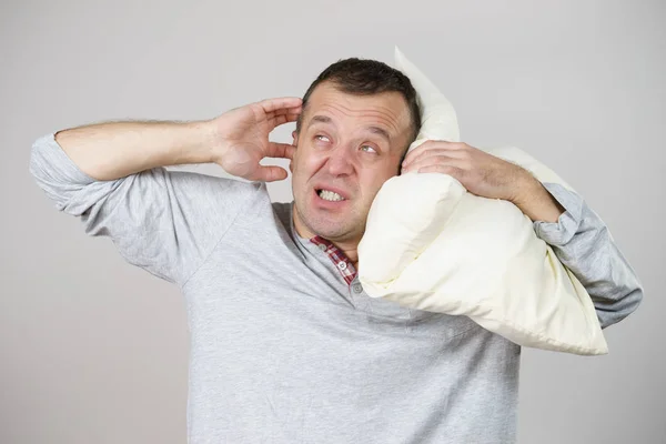 Hombre somnoliento con almohada cerrando su oreja —  Fotos de Stock