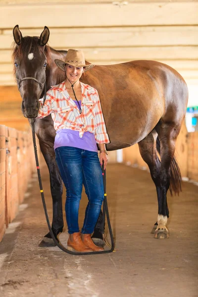 Cowgirl in piedi accanto a cavallo marrone amico — Foto Stock