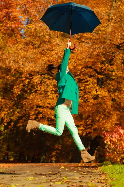 Frau springt im Herbst mit Regenschirm in Park — Stockfoto