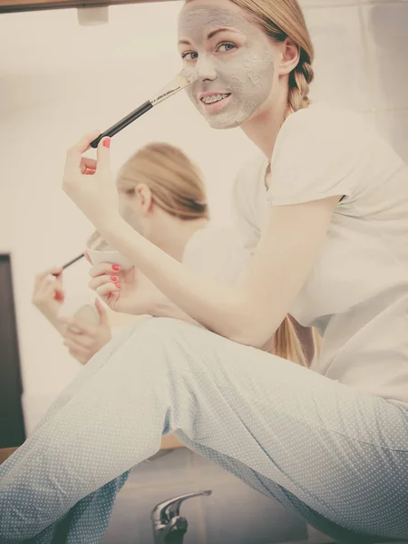 Vrouw met borstel klei modder masker toepassen op haar gezicht — Stockfoto