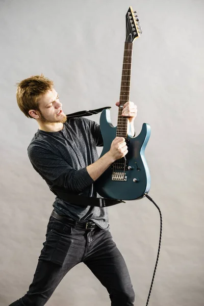 Молодой человек играет на электрогитаре — стоковое фото