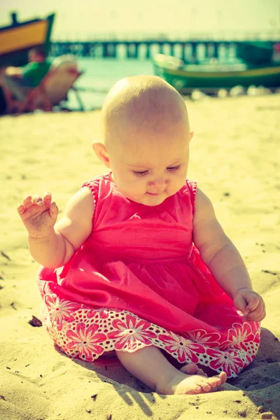 Pequeno bebê sentado e brincando na praia — Fotografia de Stock