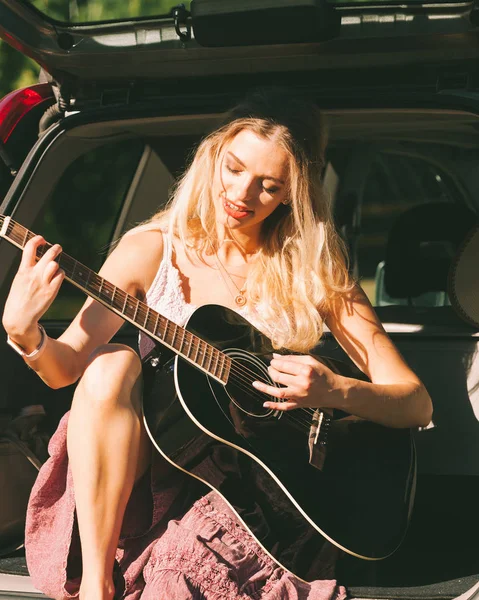 Meisje met gitaar op hatchback auto — Stockfoto