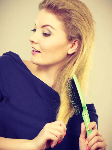 Vrouw haar lange blonde haren borstelen — Stockfoto