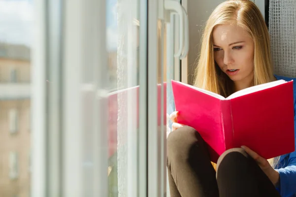 Vrouw leest op vensterbank — Stockfoto