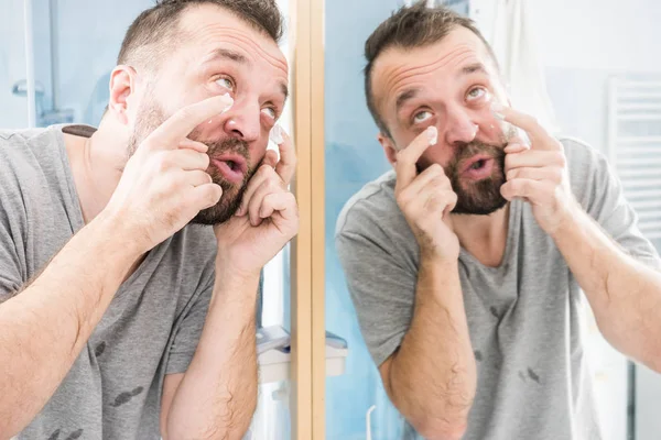 Мужчина наносит крем для увлажнения в ванной комнате — стоковое фото