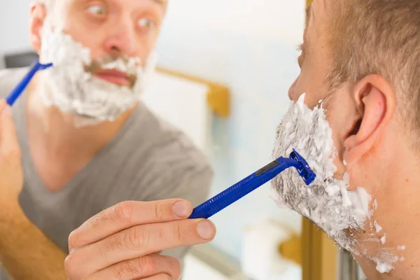 Mann rasiert sich seinen Bart im Badezimmer — Stockfoto