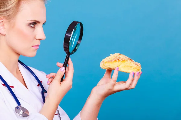 Doutor com lupa examinando alimentos doces — Fotografia de Stock