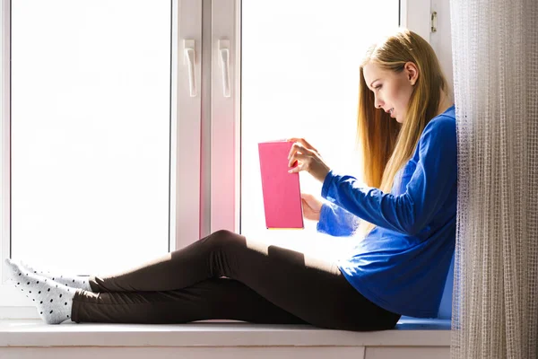 Mujer sentada en el alféizar de la ventana leyendo libro en casa —  Fotos de Stock