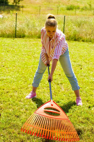 Donna che usa rastrello per pulire il giardino — Foto Stock