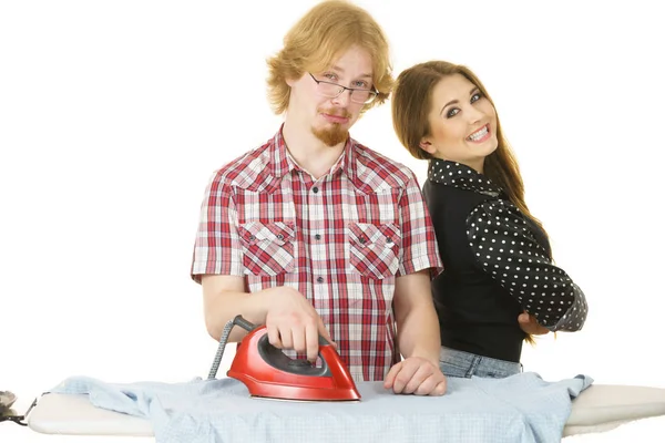 Mujer feliz y hombre aburrido planchando ropa — Foto de Stock