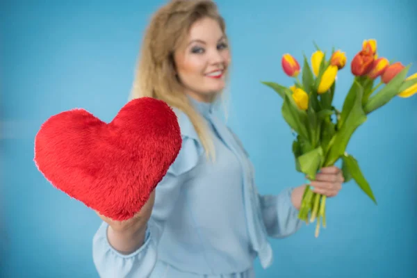 Vrouw houdt tulpen en rood hart — Stockfoto