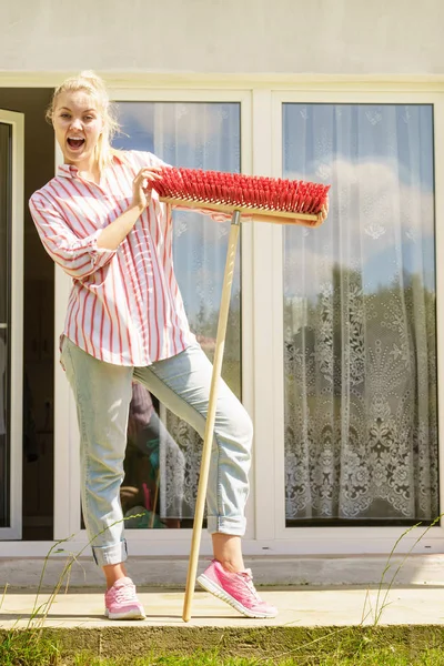 Egy nő seprűvel takarítja fel a hátsó udvart. — Stock Fotó