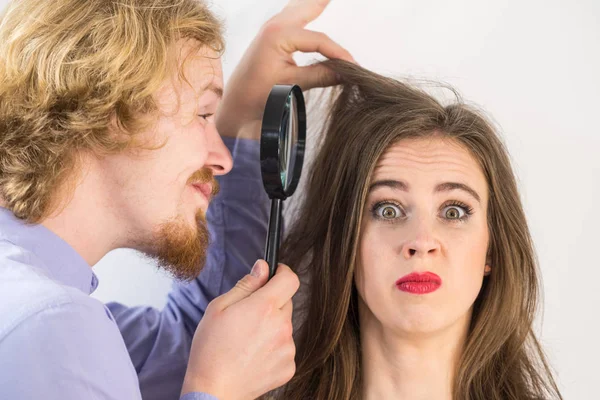 Чоловік дивиться на волосся жінки через збільшувач — стокове фото