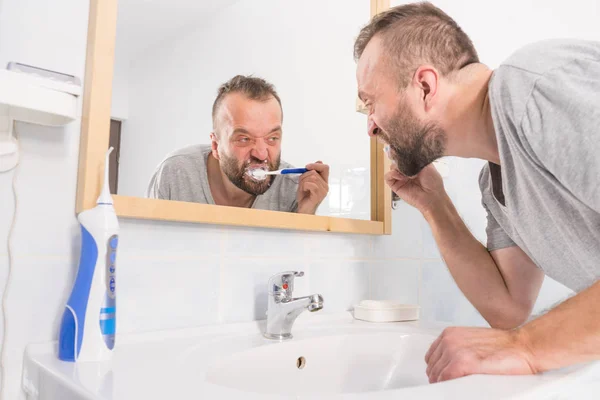 Hombre cepillándose los dientes en el baño —  Fotos de Stock